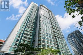 Toronto (Waterfront Communities) condo for rent - A tall building with many windows is under a blue sky with clouds.