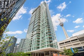Toronto (Waterfront Communities) condo for rent - A tall, modern building with a glass facade stands in front of the CN Tower.