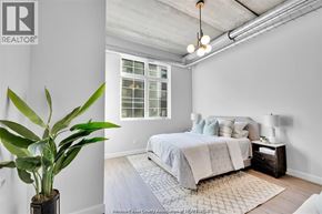 Tecumseh apartment for rent - A bedroom with a bed, a potted plant, and a rug.