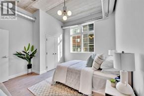 Tecumseh apartment for rent - A bedroom with a bed, a potted plant, and a window with a view of a building.