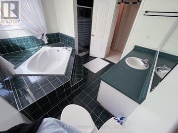Barrie (Holly) apartment for rent - A bathroom with a black and white tiled floor and a white bathtub.