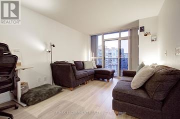 Toronto (Islington-City Centre West) condo for rent - A living room with a brown couch and a black chair.