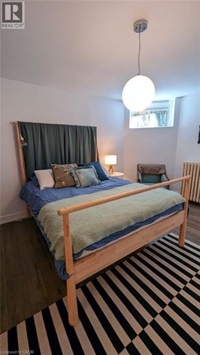 St. Catharines apartment for rent - A bedroom with a bed, a chair, and a striped rug.