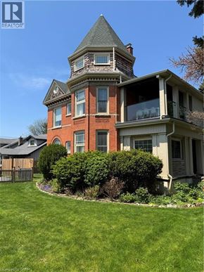 St. Catharines apartment for rent - A large red brick house with a tower and a well kept lawn.