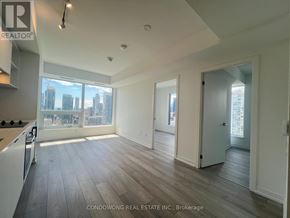 Toronto (Church-Yonge Corridor) condo for rent - A spacious, empty room with wood flooring and a large window overlooking a city skyline.
