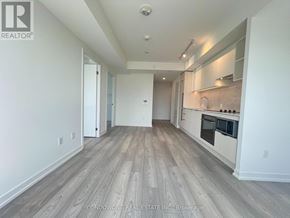 Toronto (Church-Yonge Corridor) condo for rent - A spacious room with wood flooring and a kitchen area in the background.