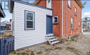 Smiths Falls apartment for rent - A small house with a blue door and a red brick building behind it.