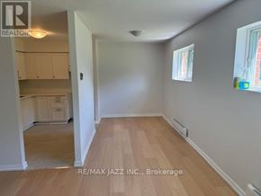 Oshawa (O'neill) multi-family for rent - A room with wooden flooring and white walls, with a window on the right side.