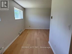 Oshawa (O'neill) multi-family for rent - A room with wooden flooring and a window on the left wall.