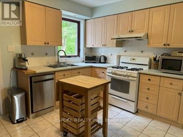 Toronto (Greenwood-Coxwell) apartment for rent - A kitchen with wooden cabinets and a white stove top oven.