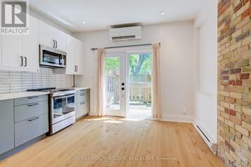 Toronto (South Riverdale) triplex for rent - A kitchen with white cabinets and a brick wall.