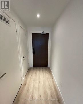 Kitchener condo for rent - A hallway with a wooden floor and a brown door.