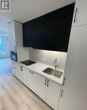 Kitchener condo for rent - A kitchen with white cabinets and black countertops.