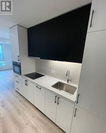 Kitchener condo for rent - A kitchen with white cabinets and black countertops.