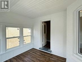 St. Thomas fourplex for rent - A room with white walls and wooden flooring, with a window on the left and a doorway on the right.