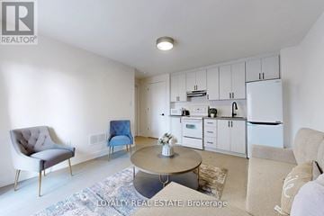 Toronto (Downsview-Roding-Cfb) townhouse for rent - A well-lit kitchen with white appliances and a dining area with a round table and chairs.
