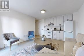 Toronto (Downsview-Roding-Cfb) townhouse for rent - A well-lit kitchen with white appliances and a dining area with a round table and chairs.