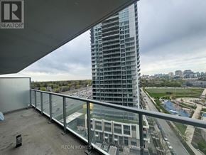 Toronto (Bayview Village) condo for rent - A tall glass building stands behind a balcony with a view of the city.