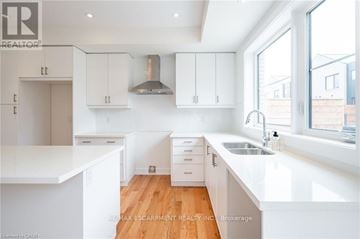 Burlington (Rose) townhouse for rent - A modern kitchen with white cabinets and a wooden floor.