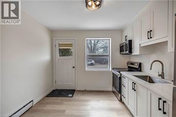London apartment for rent - A kitchen with white cabinets and a black stove top oven.