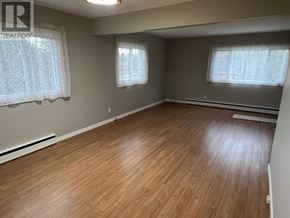 Richards Landing apartment for rent - A room with wooden flooring and two windows with curtains.