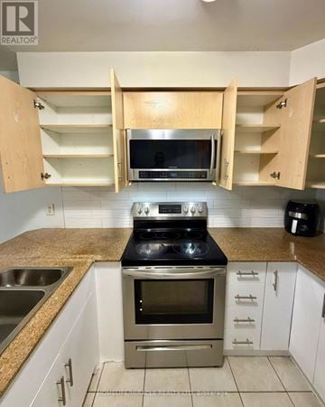 Mississauga (Malton) condo for rent - A kitchen with a stove top oven and microwave.