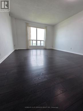 Toronto (Woburn) condo for rent - A room with dark wood flooring and a window letting in light.