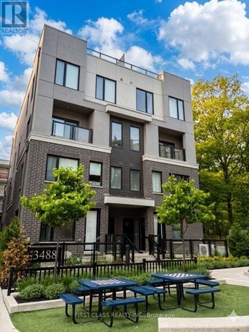 Mississauga (Erin Mills) townhouse for rent - A modern apartment building with a green lawn in front.