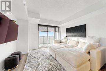 Pickering (Bay Ridges) condo for rent - A living room with a large couch and a window with a view of the ocean.