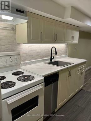 Toronto (Danforth) apartment for rent - A white stove top oven with a black handle is in a kitchen with white cabinets.