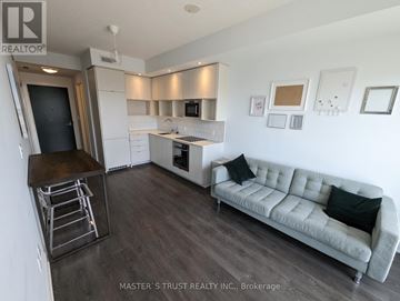 Toronto (Church-Yonge Corridor) condo for rent - A living room with a grey couch and a kitchen area in the background.