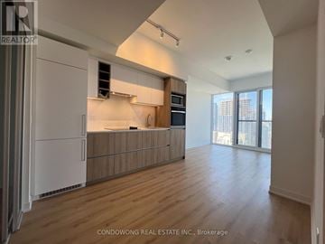 Toronto (Moss Park) condo for rent - A spacious kitchen with wooden floors and a large window.