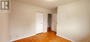 Toronto (Woburn) apartment for rent - A white room with wood floors and a Realty logo.