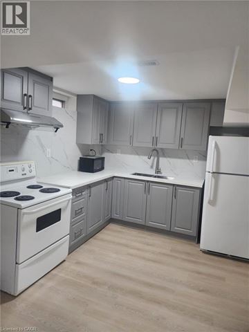 Kitchener apartment for rent - A kitchen with white appliances and grey cabinets.