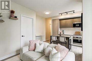 Toronto (Waterfront Communities) condo for rent - A living room with a couch and a kitchen area in the background.