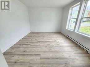 St. John's multi-family for rent - A room with wooden flooring and a window showing a view of a street.
