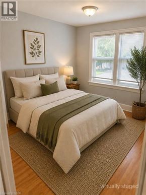 Stoney Creek apartment for rent - A bedroom with a bed, pillows, a lamp, a plant, and a framed picture on the wall.