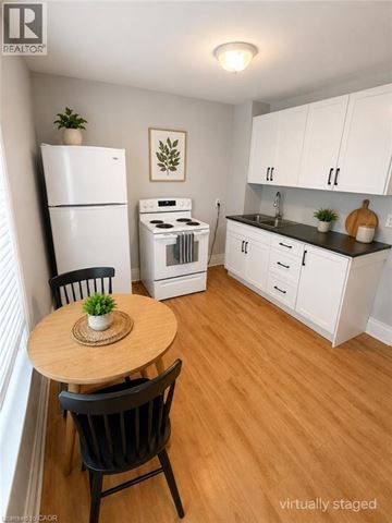 Stoney Creek apartment for rent - A kitchen with a table and chairs in front of a refrigerator and oven.