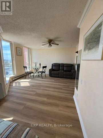 Toronto (Eglinton East) condo for rent - A living room with a black sofa and a ceiling fan.
