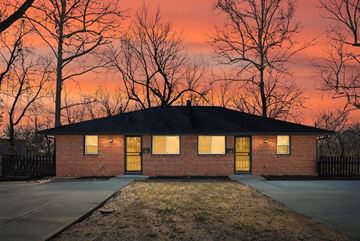 Independence apartment for rent - A house with a black roof and yellow doors is surrounded by bare trees.
