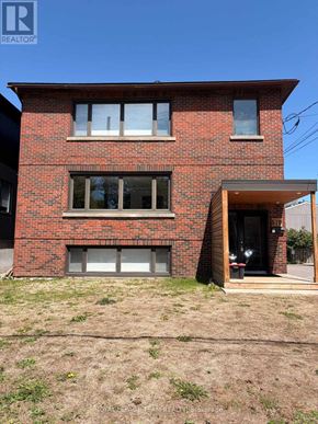 Ottawa apartment for rent - A red brick house with a large window and a doorway leading to a balcony.