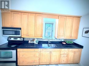 Toronto (Wexford-Maryvale) apartment for rent - A kitchen with wooden cabinets and black countertops.