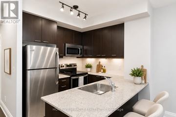 Mississauga (City Centre) condo for rent - A modern kitchen with a stainless steel refrigerator and a granite countertop.