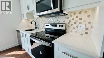 Kitchener condo for rent - A kitchen with a black stove top oven and white cabinets.
