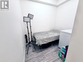 Waterloo condo for rent - A small bedroom with a bed, a floor lamp, and a small table.
