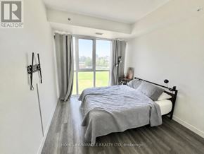 Waterloo condo for rent - A bedroom with a large bed and a view of a green field through the window.