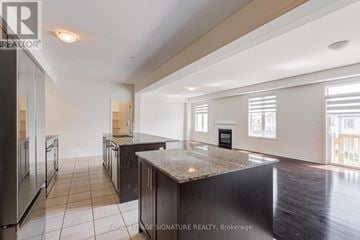 Oshawa (Kedron) apartment for rent - A spacious kitchen with dark wood cabinets and a granite countertop.