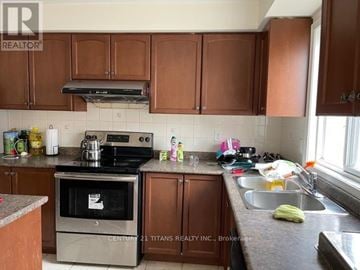 Toronto (Clairlea-Birchmount) townhouse for rent - A kitchen with brown cabinets and a stove top oven.