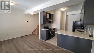 Brampton (Northwest Brampton) townhouse for rent - A realtor photo of a kitchen and living room with a staircase in the background.