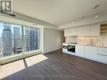 Toronto (Bay Street Corridor) condo for rent - A spacious kitchen with white cabinets and a view of the city.
